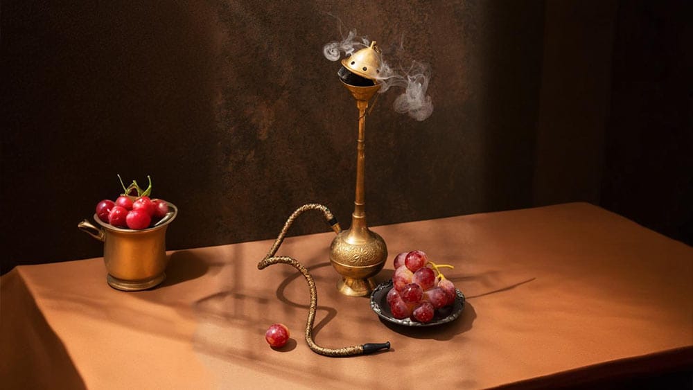 Narghilea traditionala asezata pe o masa din lemn cu struguri alaturi