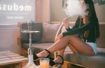 Narghilea in societatea moderna - fata care fumeaza din narghilea intr-un local