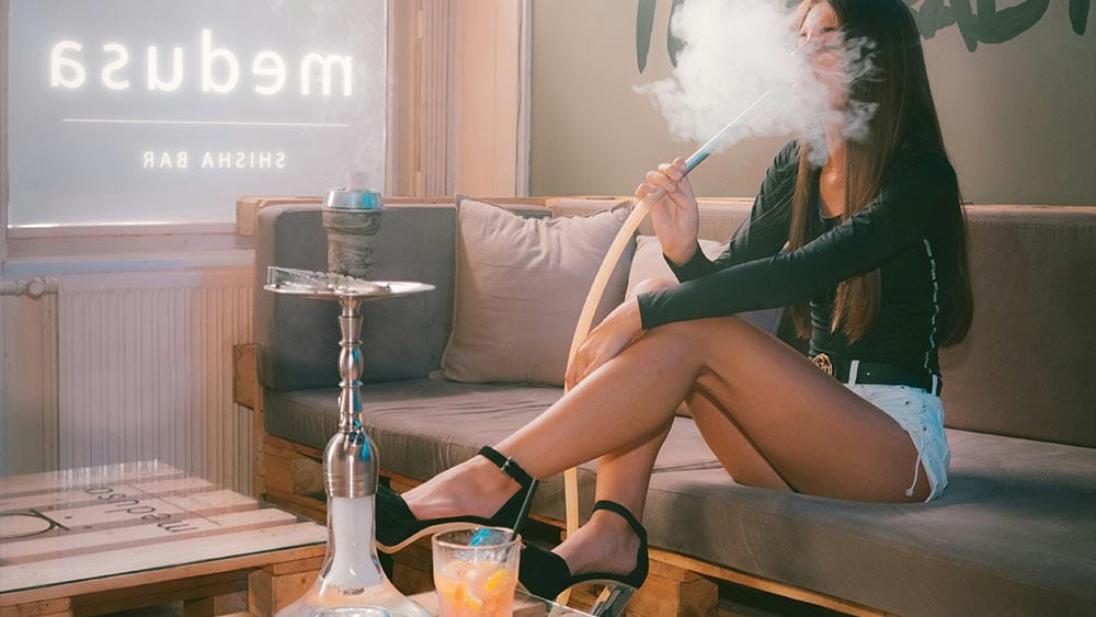 Narghilea in societatea moderna - fata care fumeaza din narghilea intr-un local