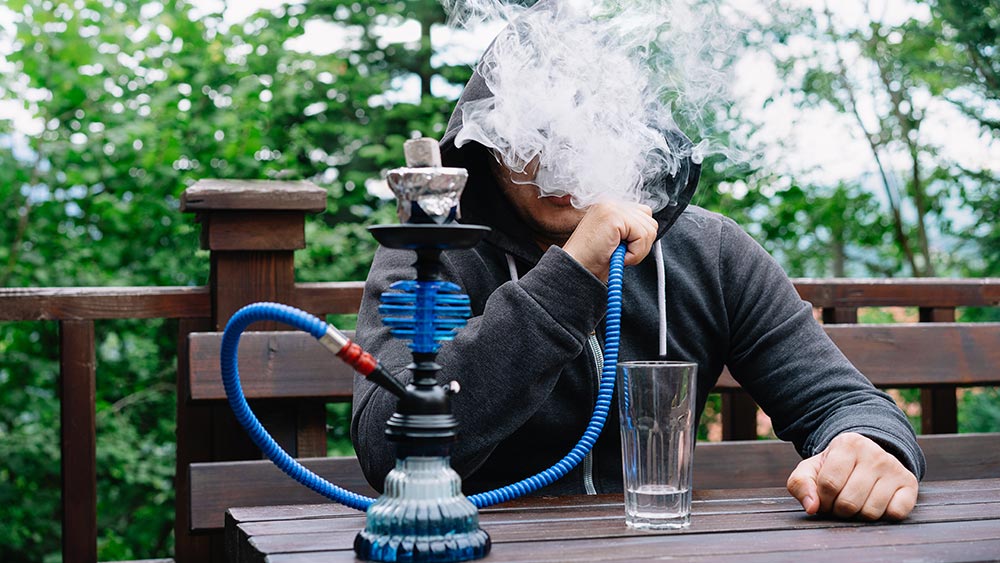 De ce narghilele portabile sunt populare - barbat care fumeaza dintr-o narghilea portabila